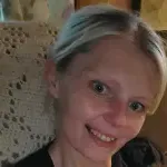 Woman posing for a selfie on a couch with a white crochet blanket behind her