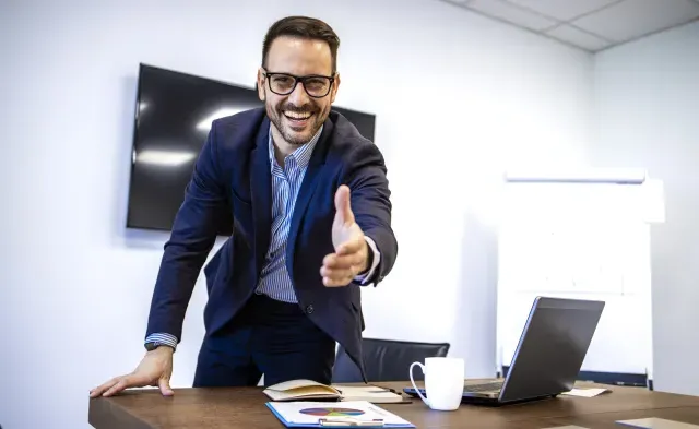 Portrait of businessman in elegant suit showing welcoming hand to the new employees.